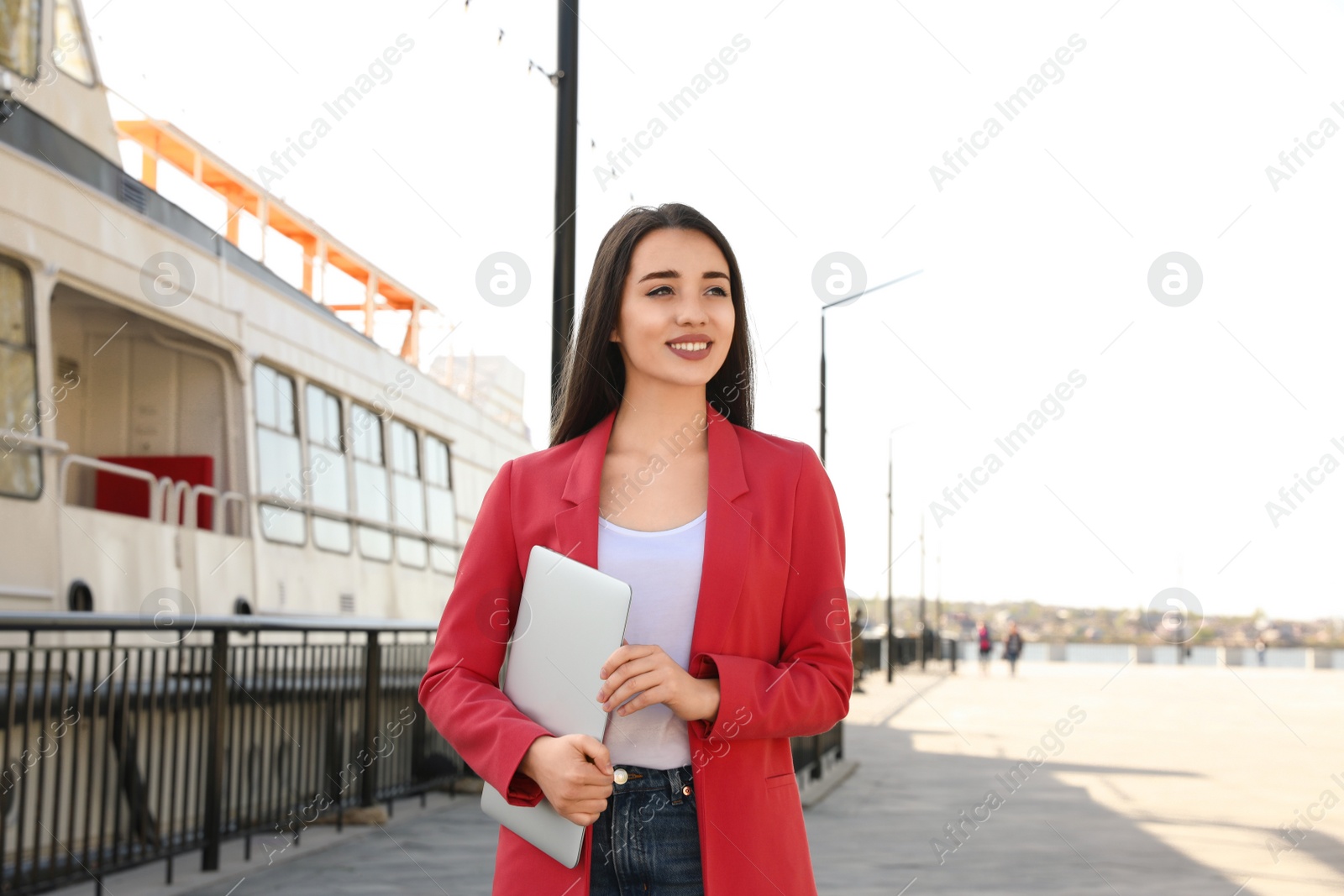 Image of Happy young woman with laptop walking outdoors