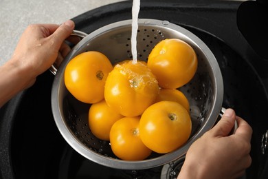 Woman washing fresh ripe yellow tomatoes, closeup