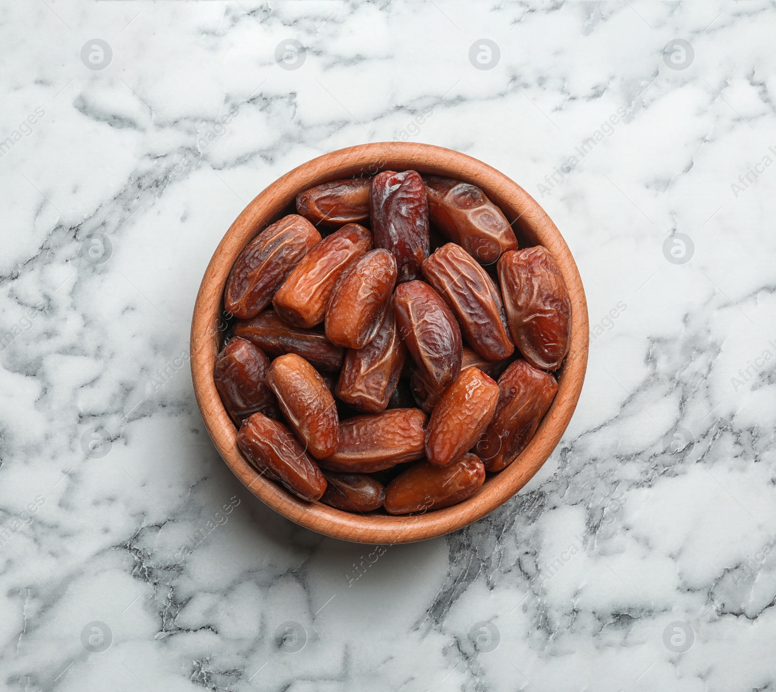 Photo of Bowl with sweet dried date fruits on marble background, top view