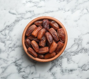 Bowl with sweet dried date fruits on marble background, top view