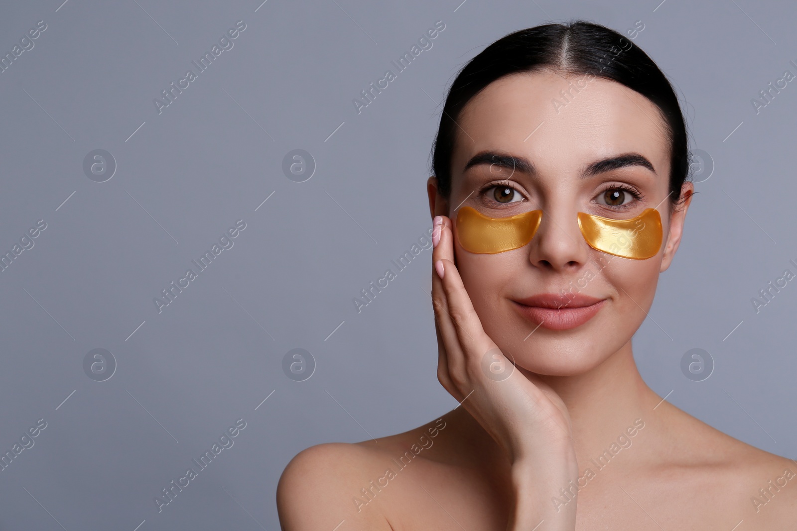 Photo of Beautiful young woman with under eye patches on grey background, space for text