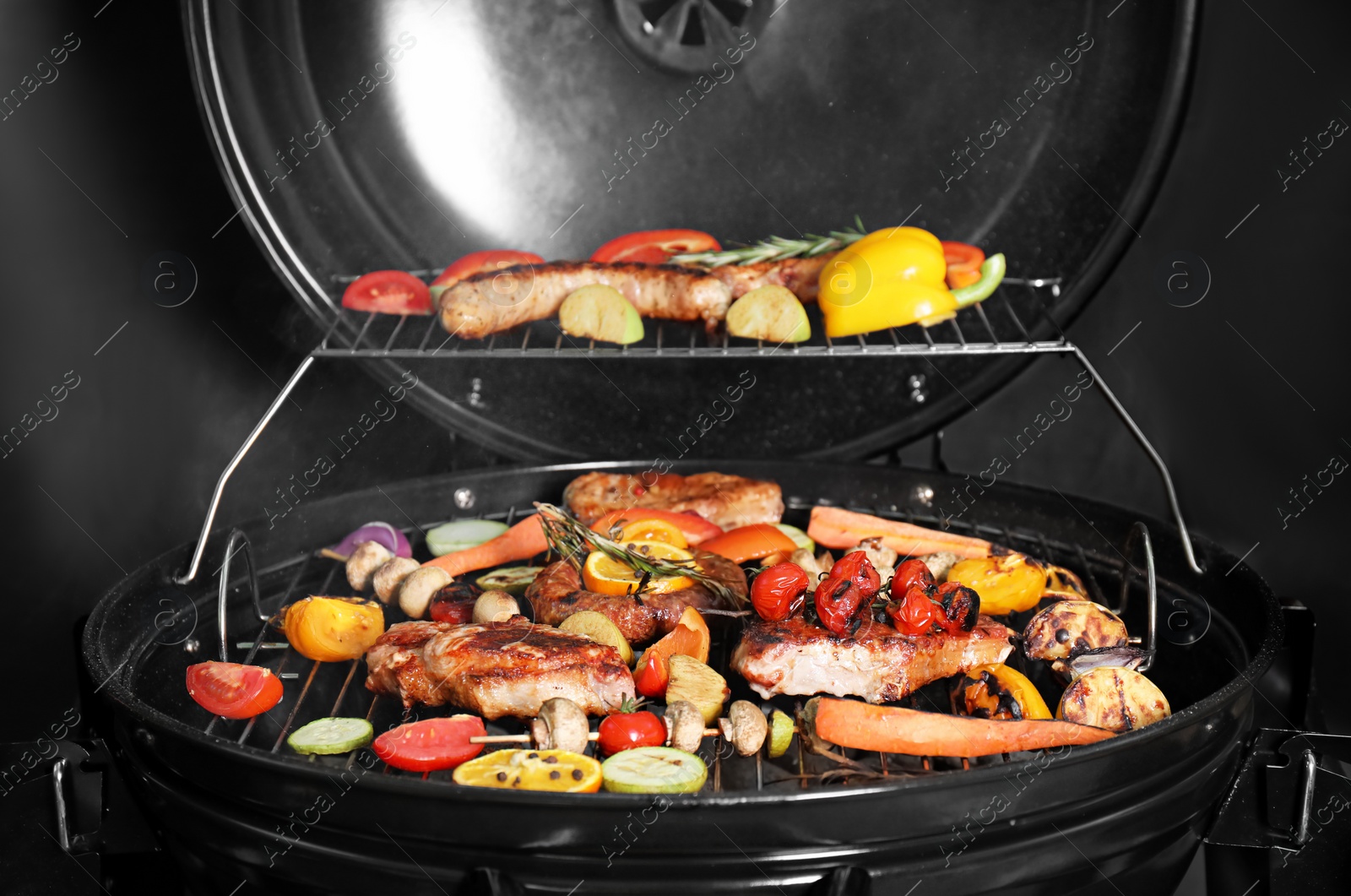 Photo of Barbecue grill with delicious cooked meat and vegetables on black background