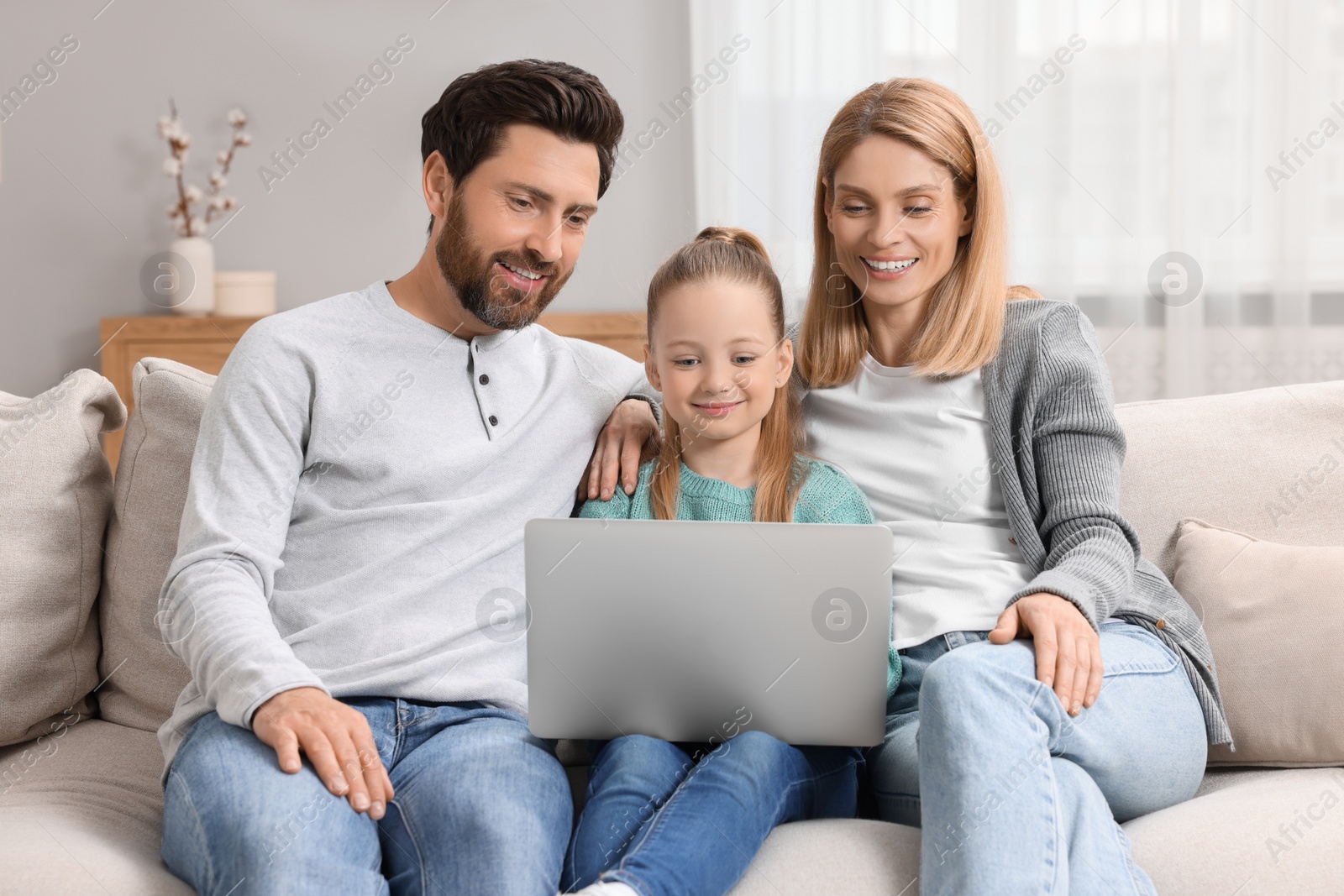 Photo of Happy family with laptop on sofa at home