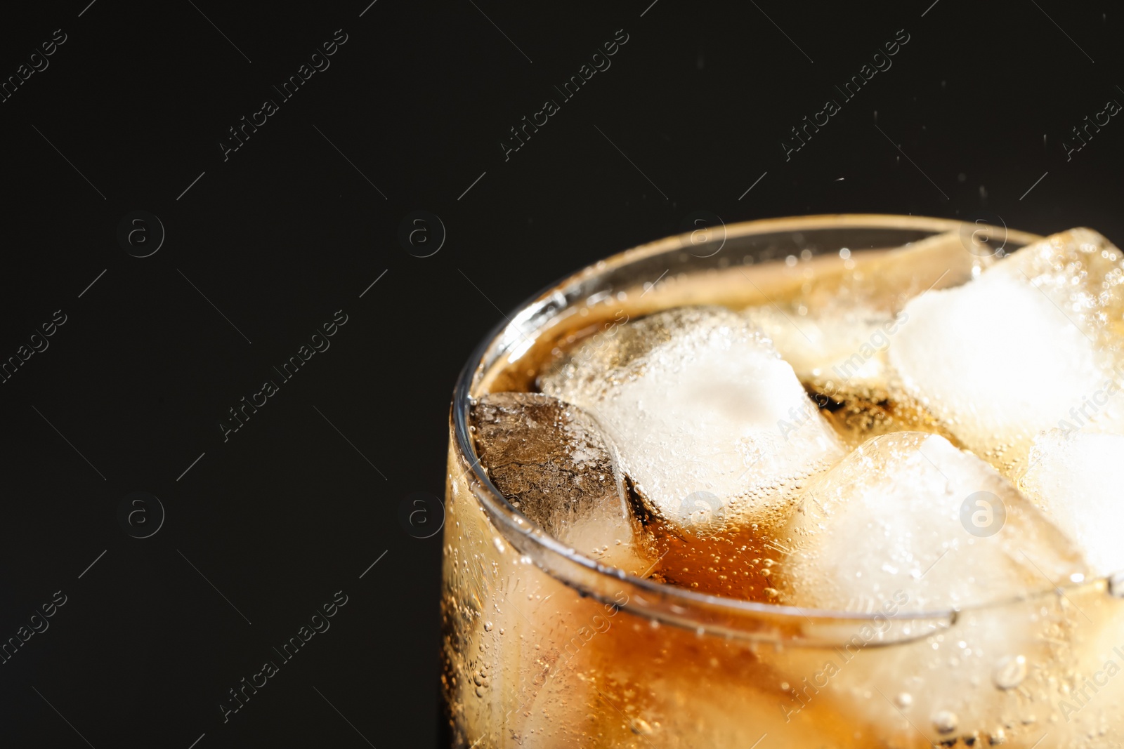 Photo of Glass of refreshing soda drink with ice cubes on black background, closeup