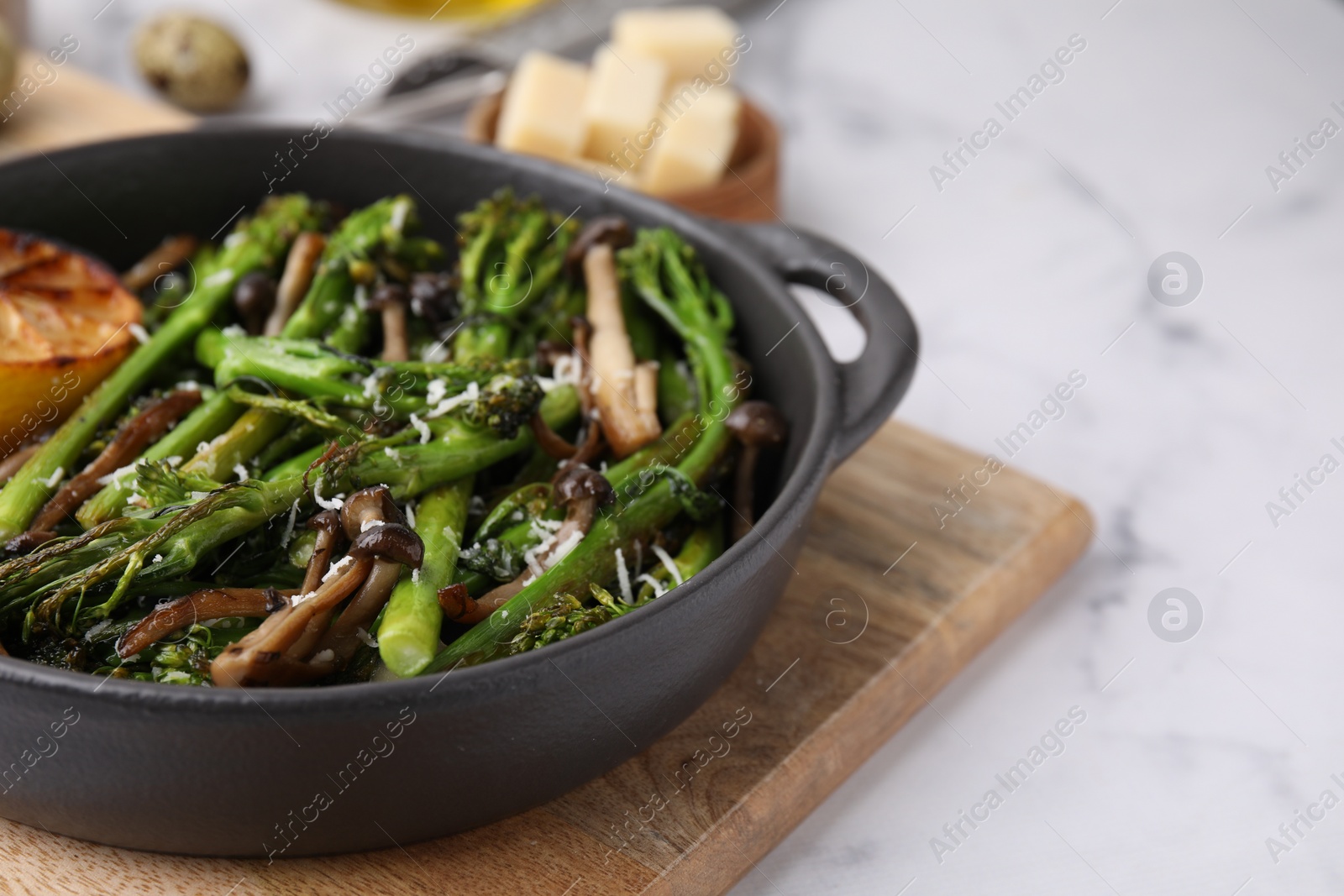 Photo of Tasty cooked broccolini, mushrooms and lemon on white marble table, closeup. Space for text