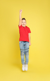 Photo of Cute little boy jumping on yellow background