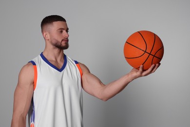 Photo of Athletic young man with basketball ball on light grey background
