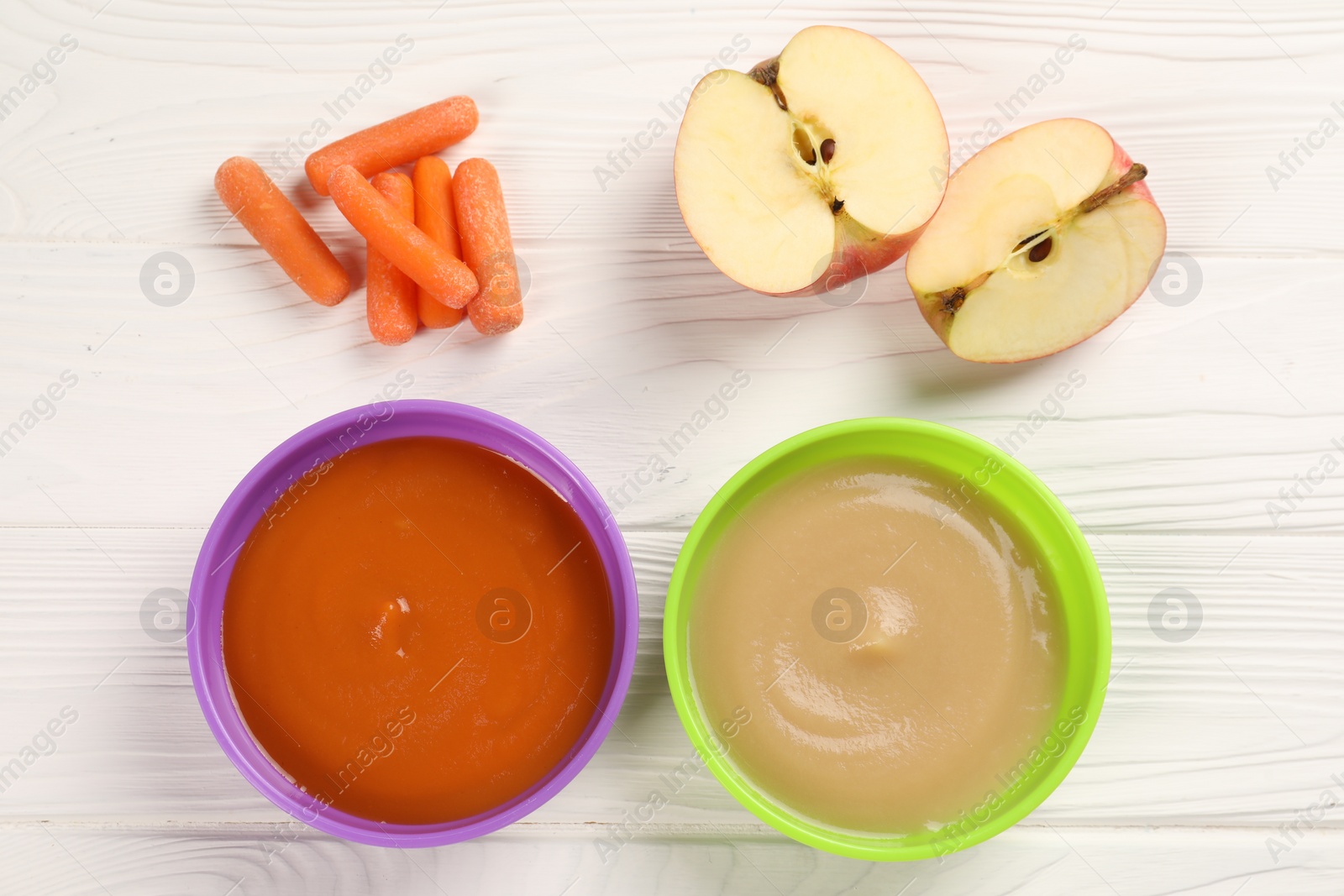 Photo of Baby food. Purees of apples and carrots in bowls on white wooden table, flat lay