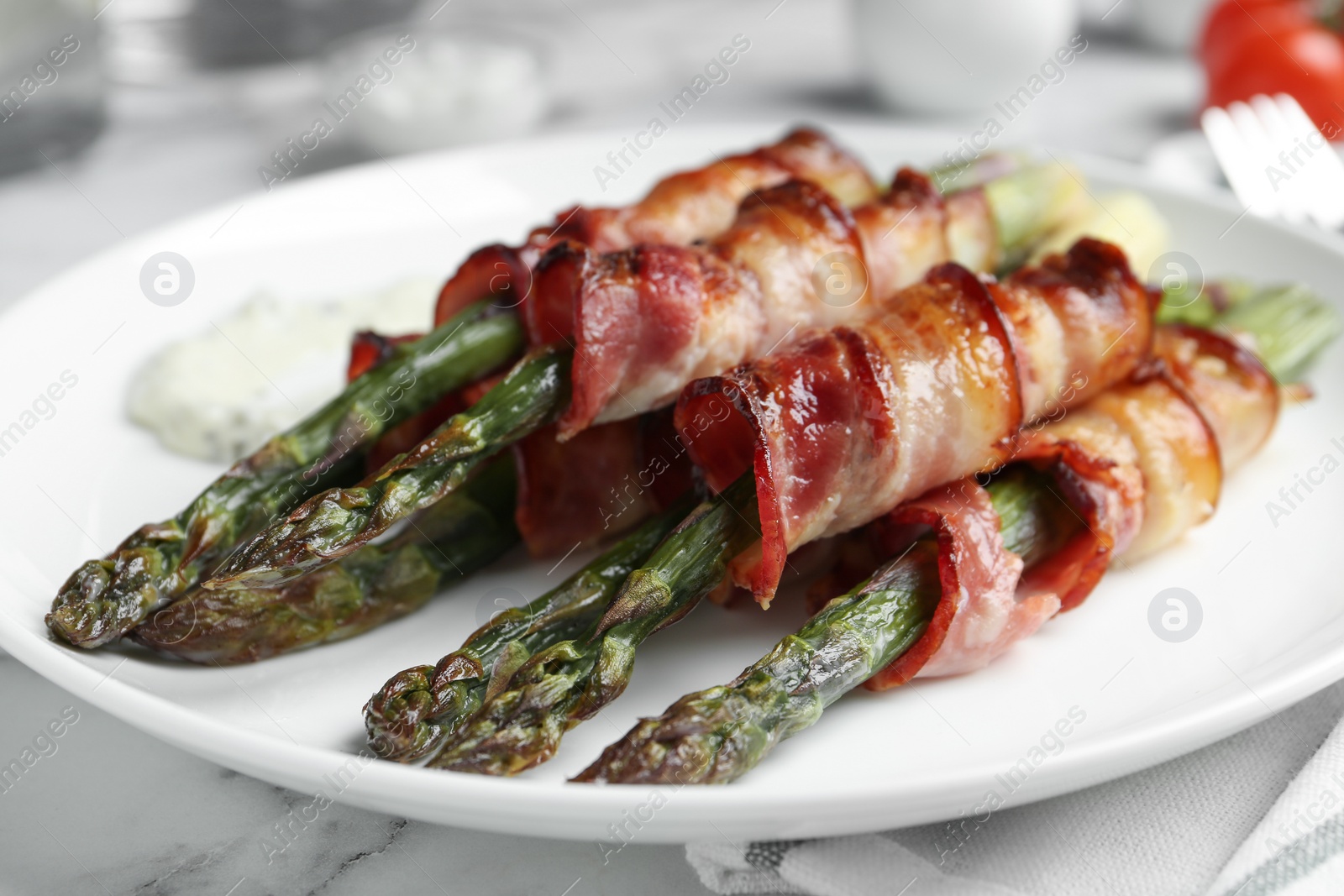 Photo of Oven baked asparagus wrapped with bacon on plate, closeup