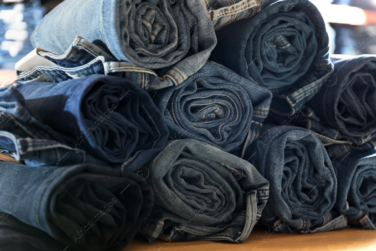 Photo of Rolled modern jeans on display in shop, closeup