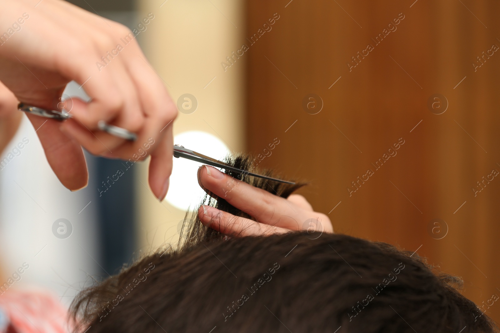 Photo of Barber making stylish haircut with professional scissors in beauty salon, closeup