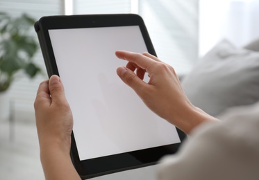 Photo of Woman using modern tablet at home, closeup. Space for design