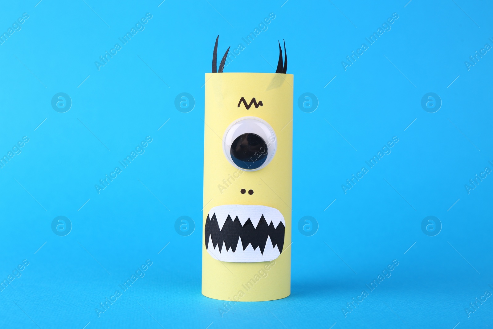 Photo of Spooky paper monster on light blue background. Handmade Halloween decoration