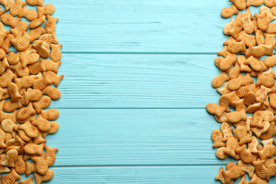 Photo of Delicious fish shaped crackers on light blue wooden table, flat lay. Space for text