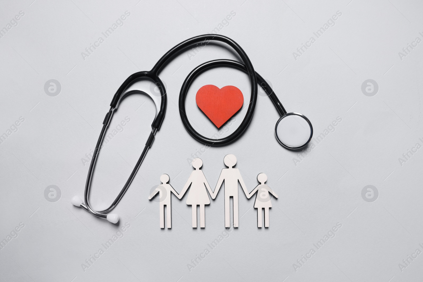 Photo of Figures of family near stethoscope and heart on white background, flat lay. Insurance concept