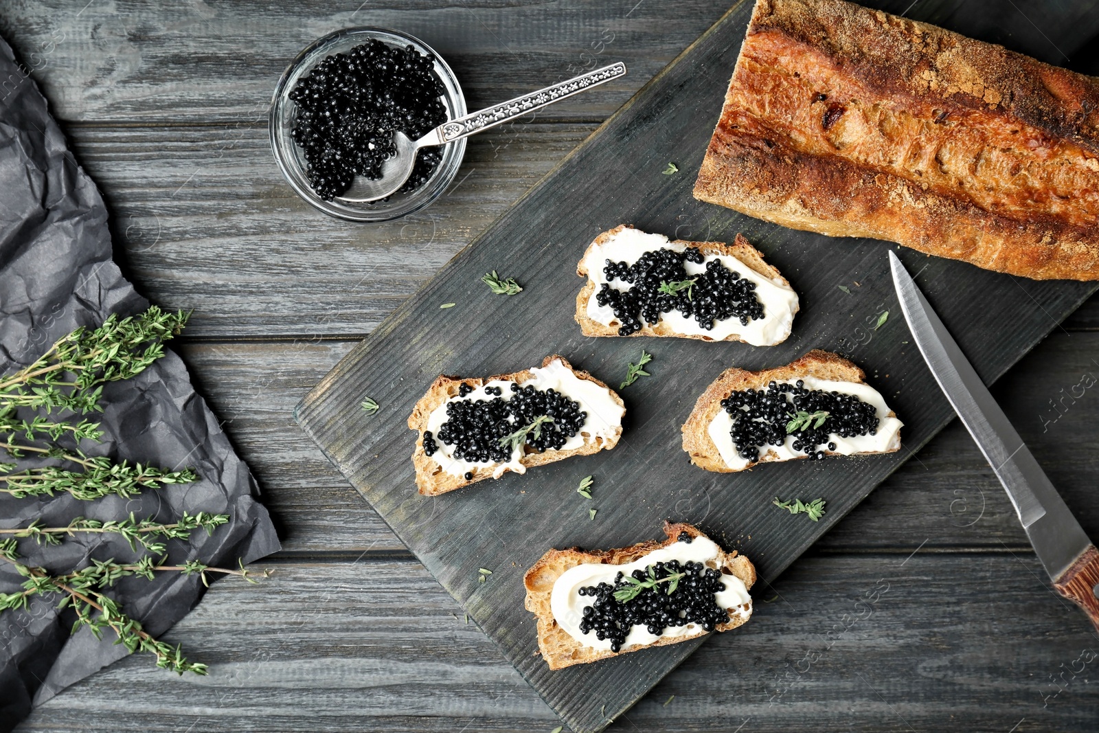 Photo of Sandwiches with black caviar and butter on wooden board