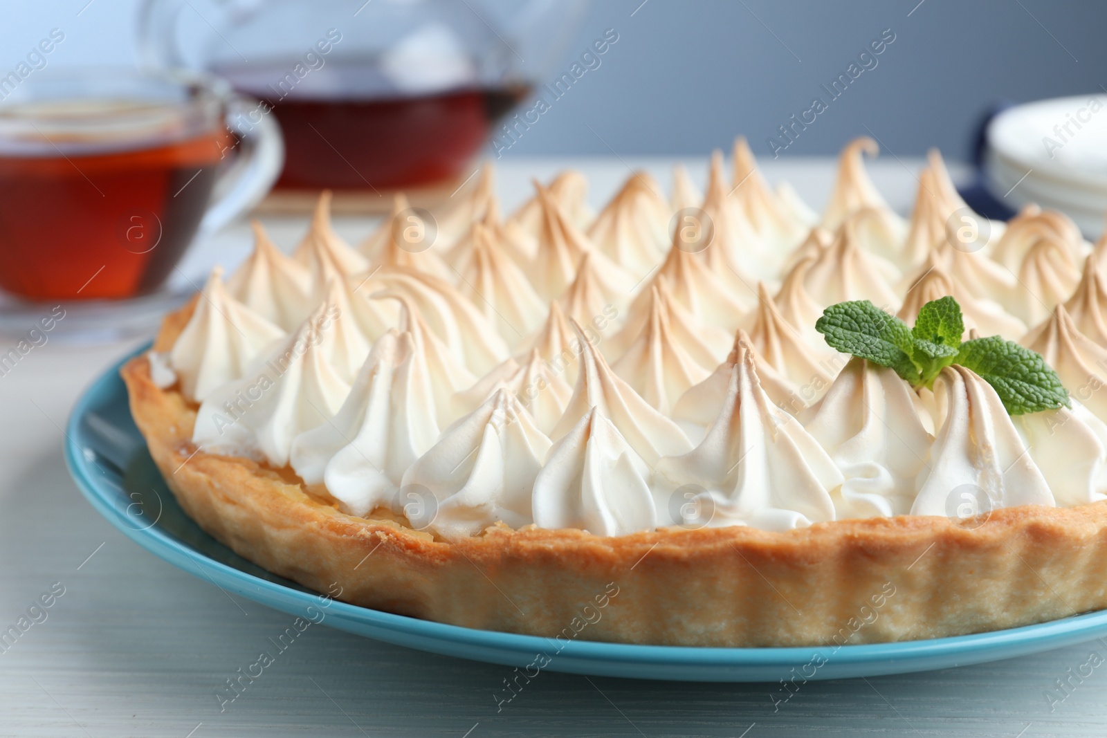 Photo of Delicious lemon meringue pie decorated with mint on  white table, closeup