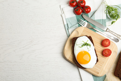 Photo of Tasty fried egg served with rye bread on white wooden table, flat lay. Space for text
