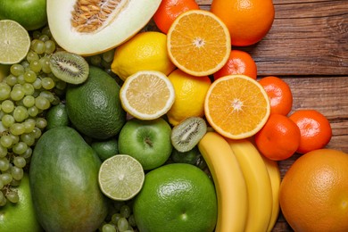 Many different fresh fruits and grapes on wooden table, flat lay