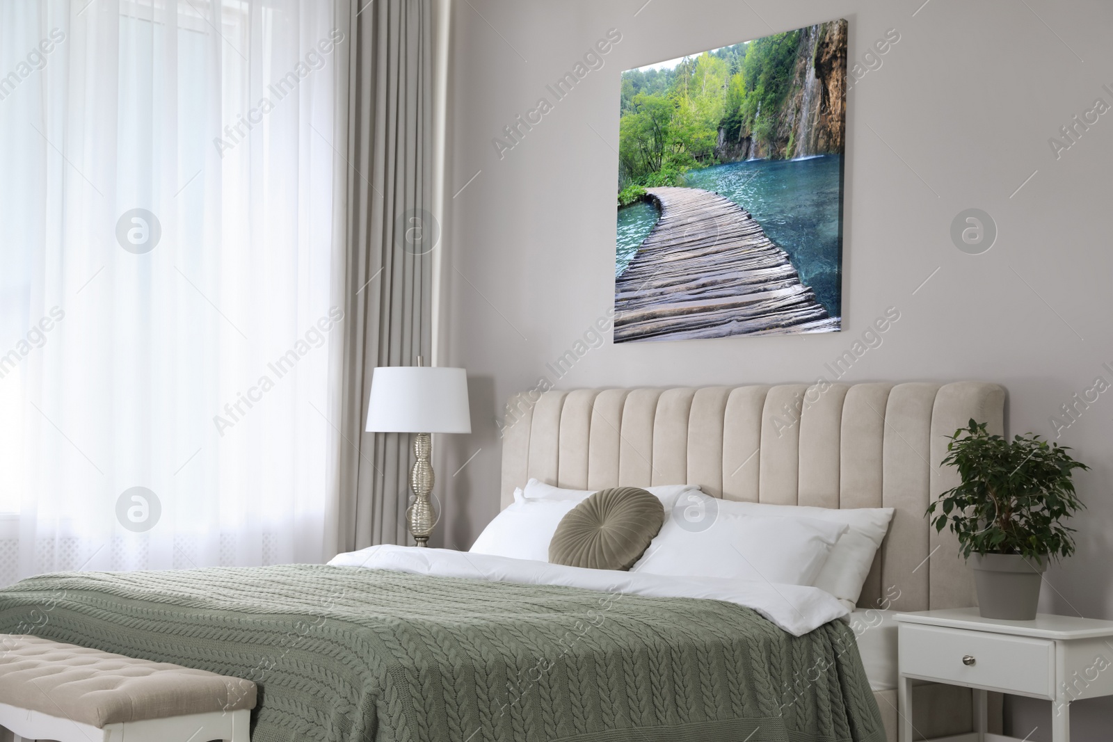 Image of Canvas with printed photo of wooden bridge over lake and waterfall on beige wall in bedroom