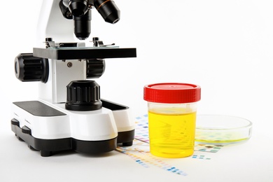 Photo of Laboratory ware with urine samples for analysis and microscope on white background