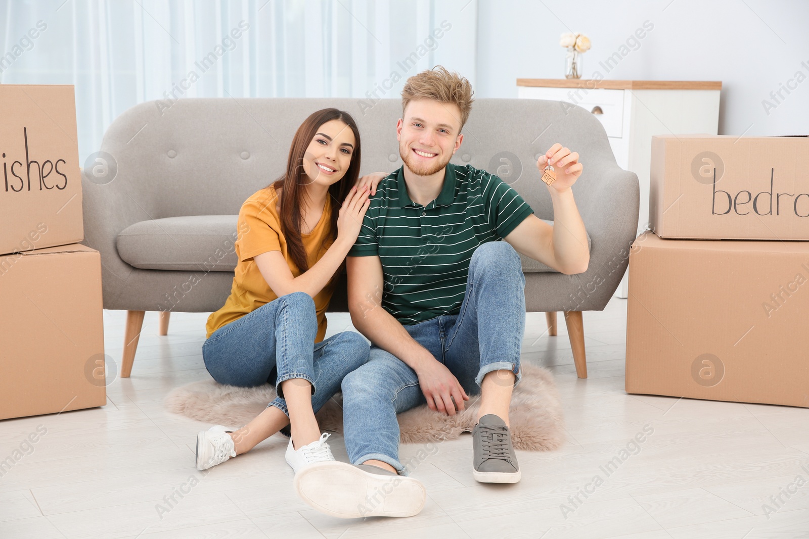 Photo of Young couple with key from their new house indoors. Moving day