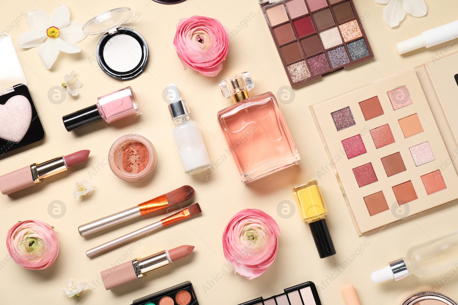 Photo of Flat lay composition with different makeup products and beautiful spring flowers on beige background