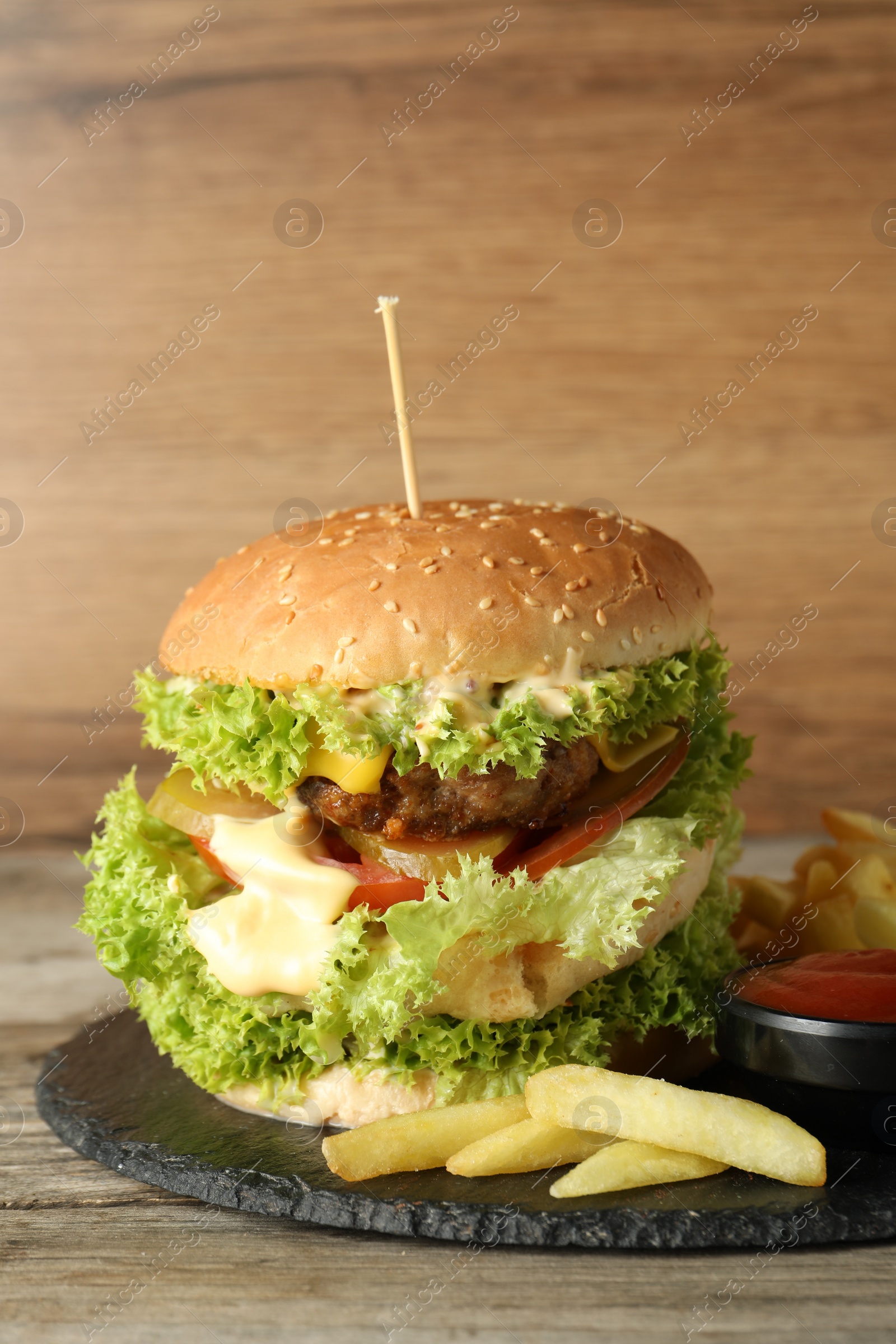 Burger with delicious patty, french fries and sauce on wooden table Photo of Burger with delicious patty, french fries and sauce on wooden table
