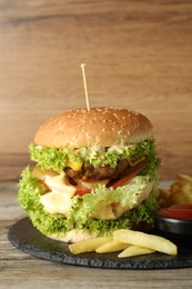 Photo of Burger with delicious patty, french fries and sauce on wooden table