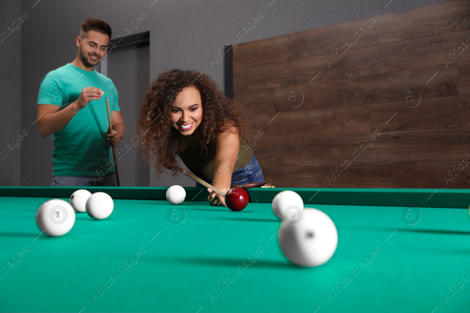 Photo of Young man and woman playing billiard indoors