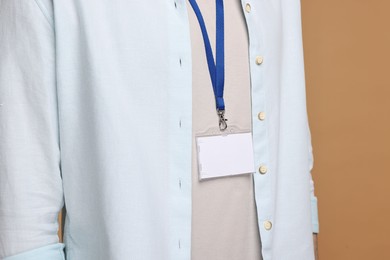 Man with empty badge on beige background, closeup