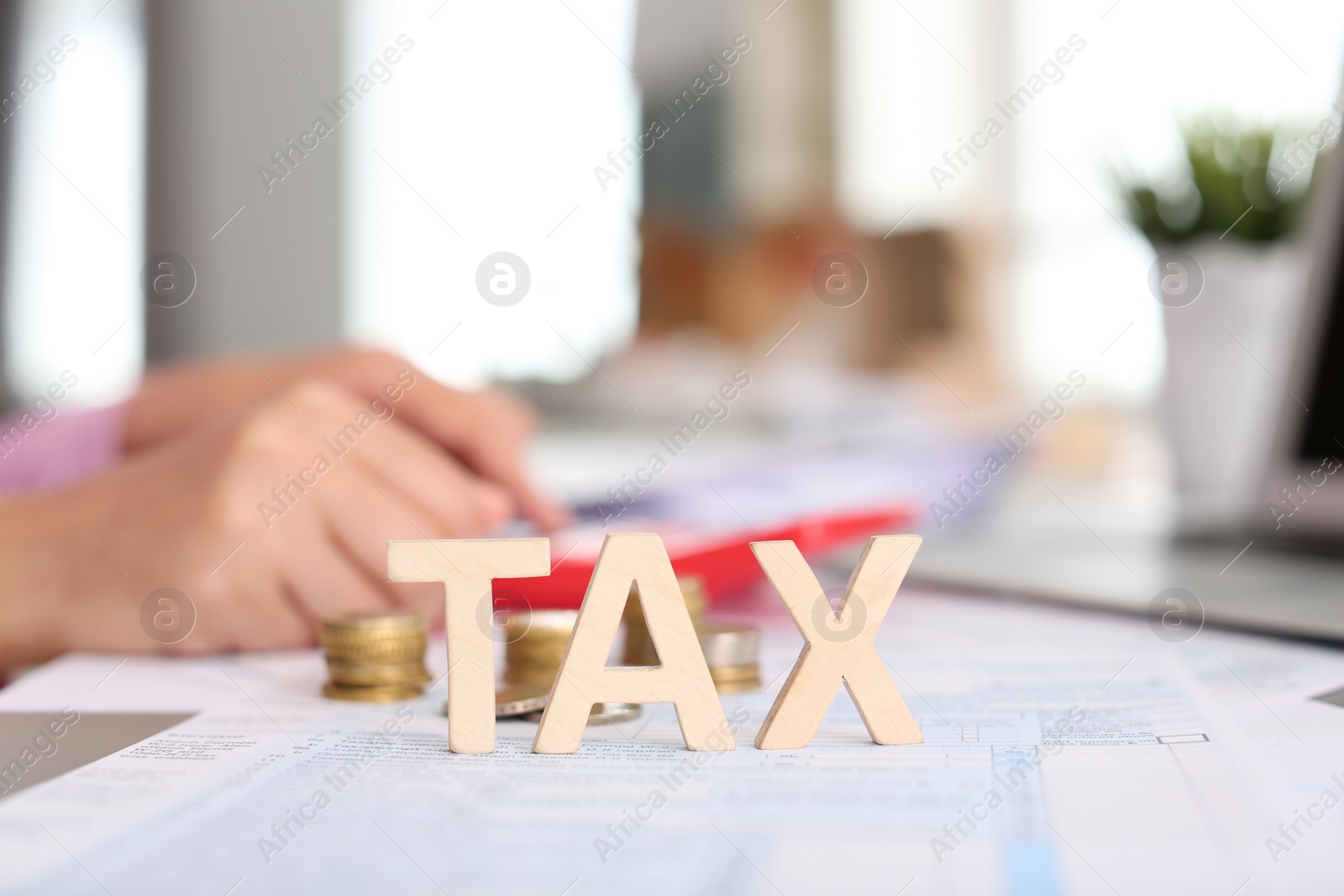 Photo of Word TAX and blurred woman on background