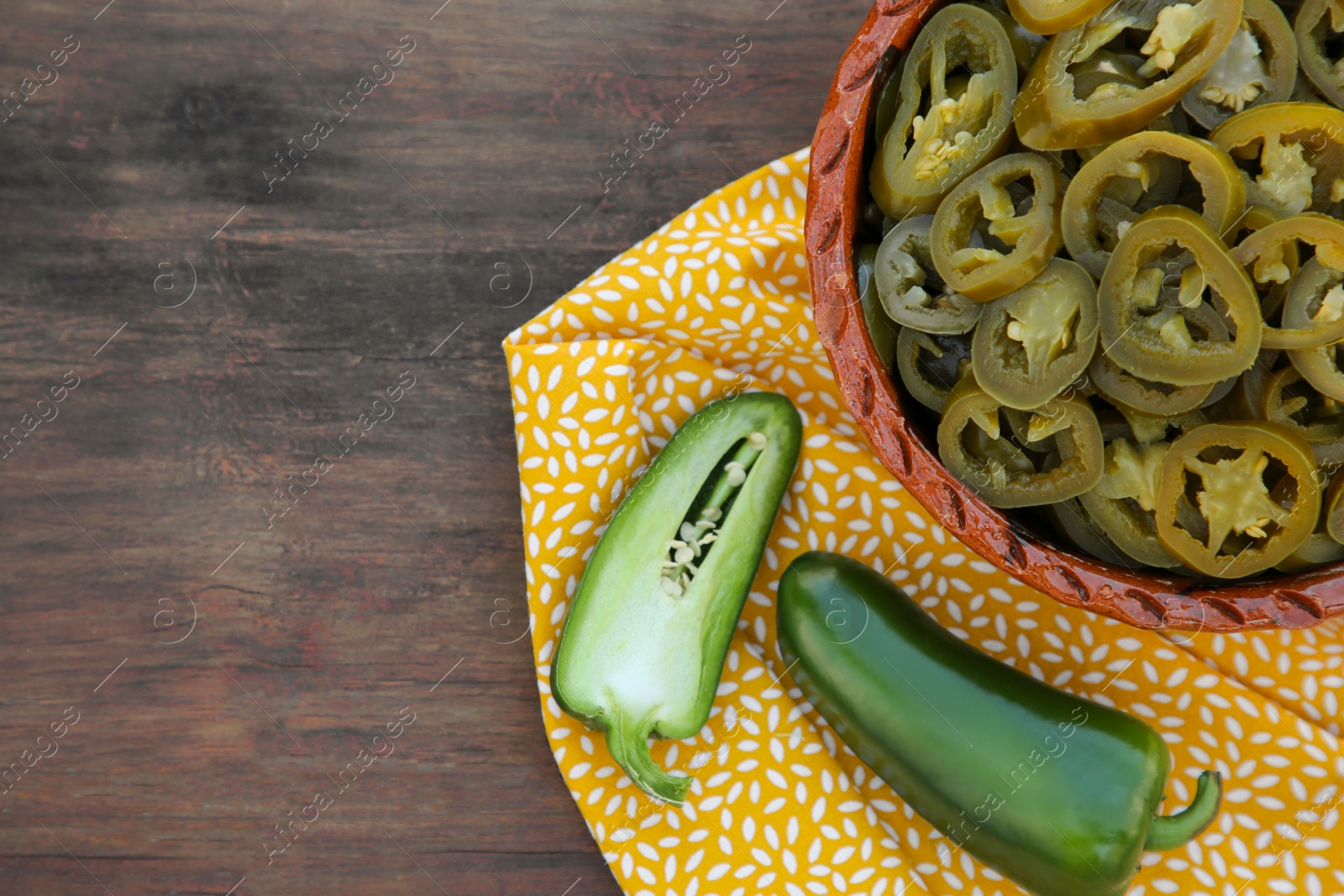 Photo of Fresh and pickled green jalapeno peppers on wooden table, top view. Space for text