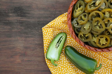 Photo of Fresh and pickled green jalapeno peppers on wooden table, top view. Space for text