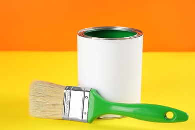 Photo of Blank can of paint with brush on color background