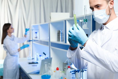 Photo of Scientist holding test tube with liquid indoors, closeup. Laboratory analysis