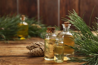 Pine essential oil, cones and branches on wooden table. Space for text