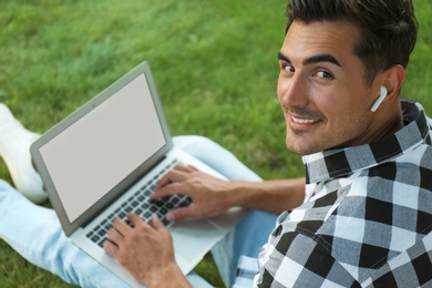 Photo of Portrait of young man with laptop outdoors. Space for design