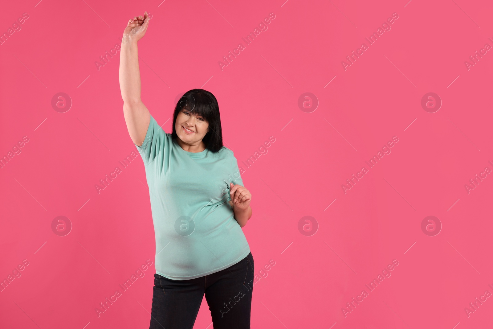 Photo of Beautiful overweight mature woman with charming smile on pink background. Space for text