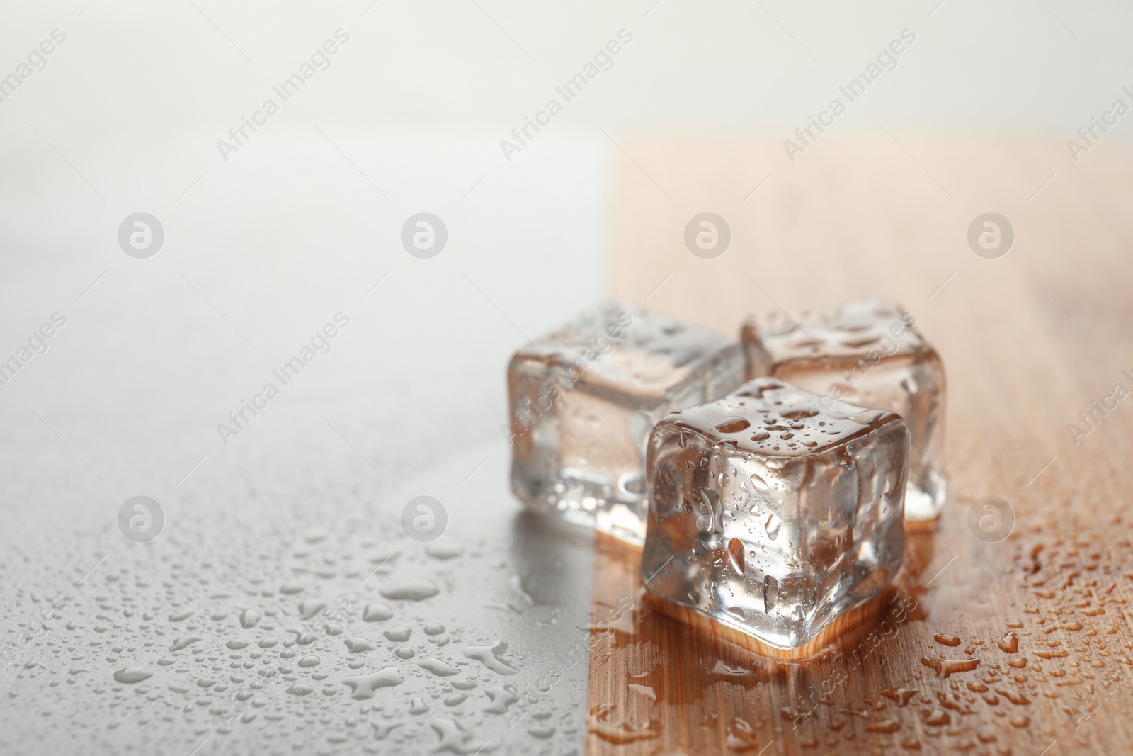 Photo of Crystal clear ice cubes with water drops on table. Space for text