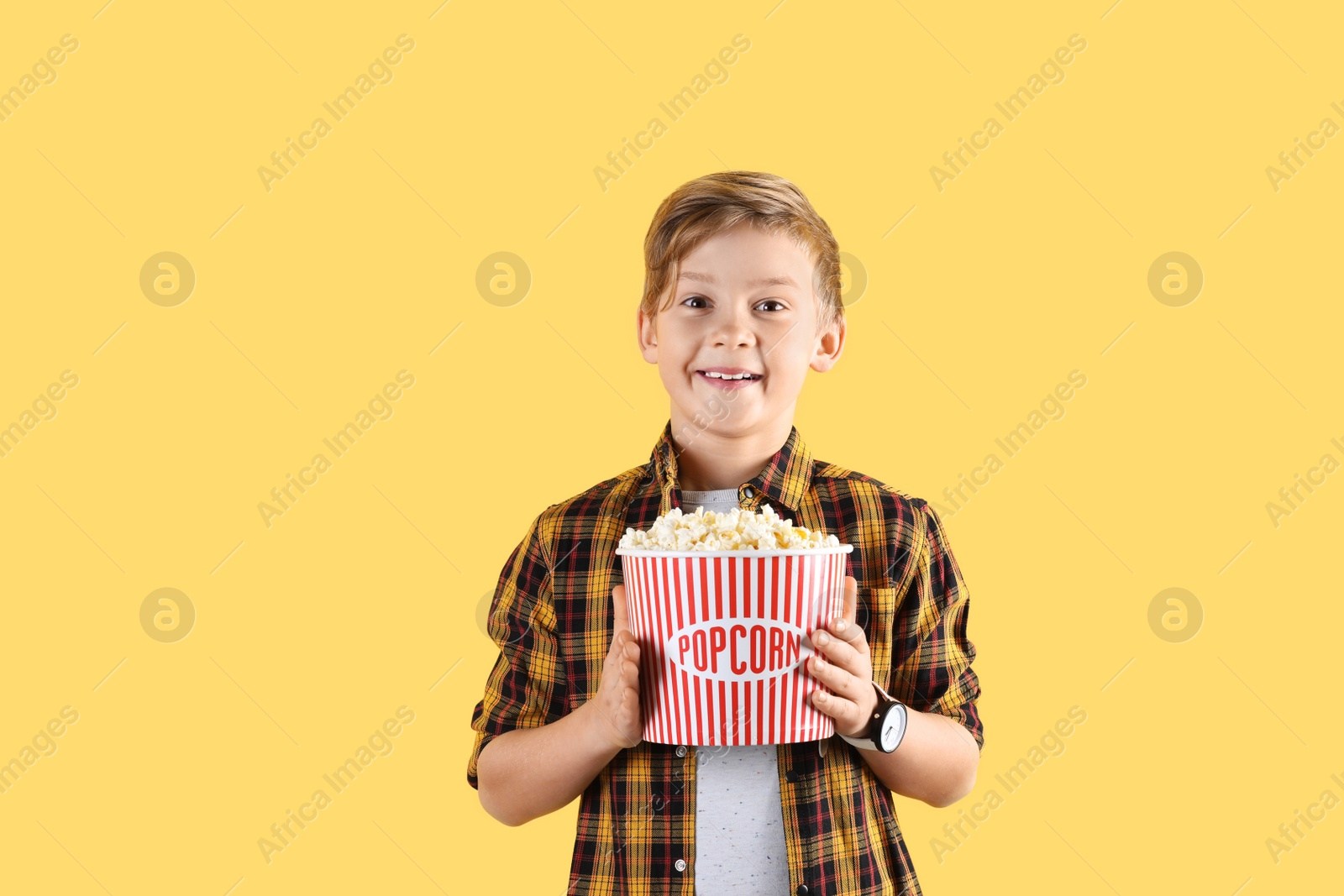 Photo of Cute boy with popcorn bucket on color background