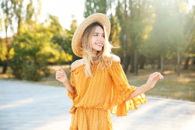 Photo of Beautiful young woman in stylish yellow dress and straw hat outdoors