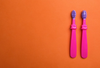 Manual toothbrushes for children on color background, top view with space for text