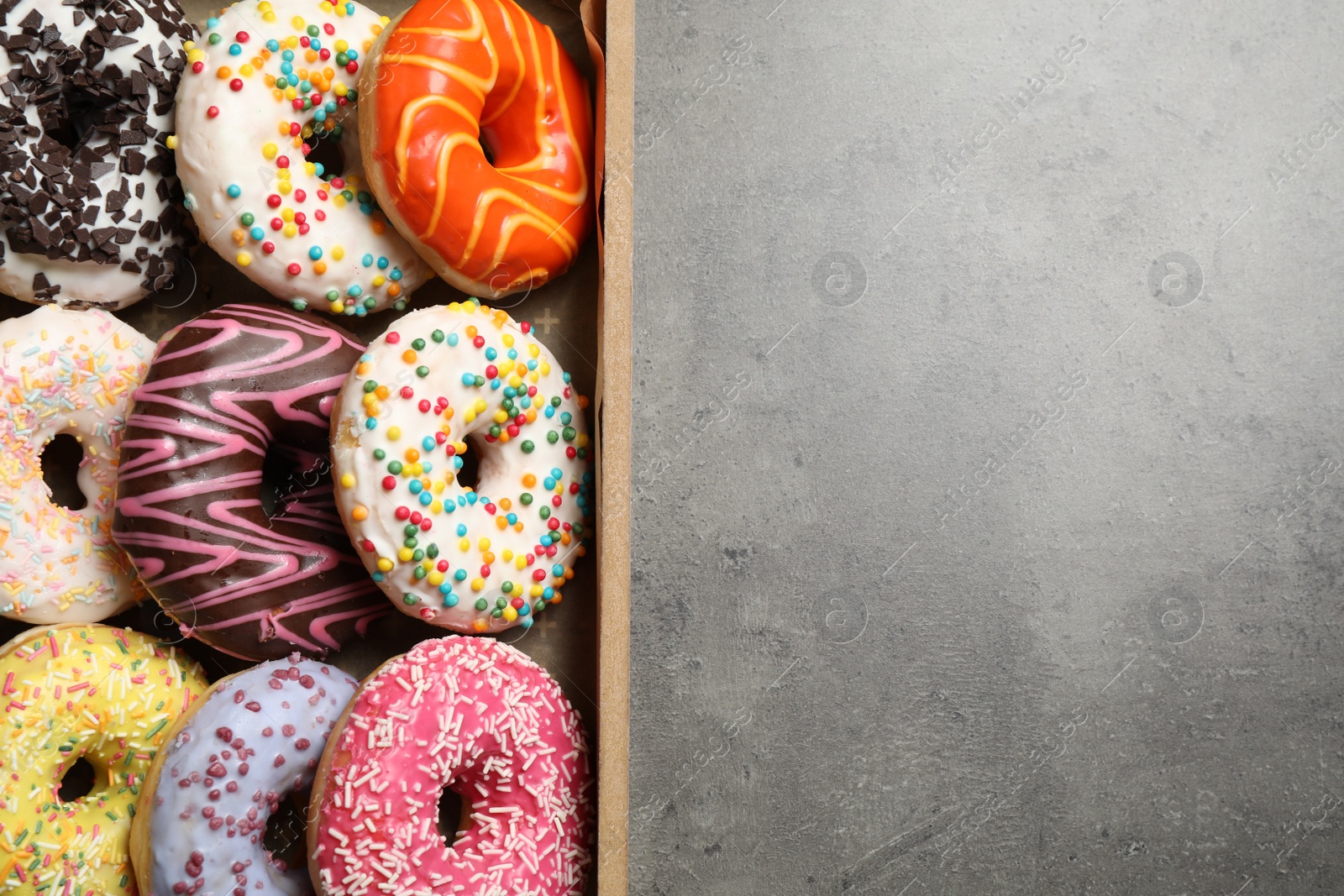 Photo of Top view of yummy donuts with sprinkles in box, space for text