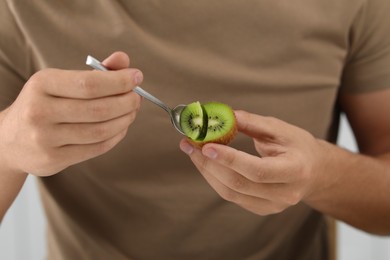 Photo of Man eating kiwi with spoon, closeup view