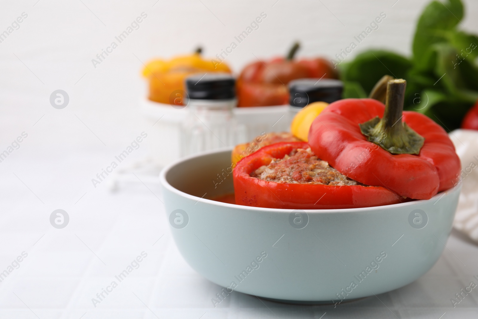 Photo of Delicious stuffed bell peppers on white tiled table. Space for text