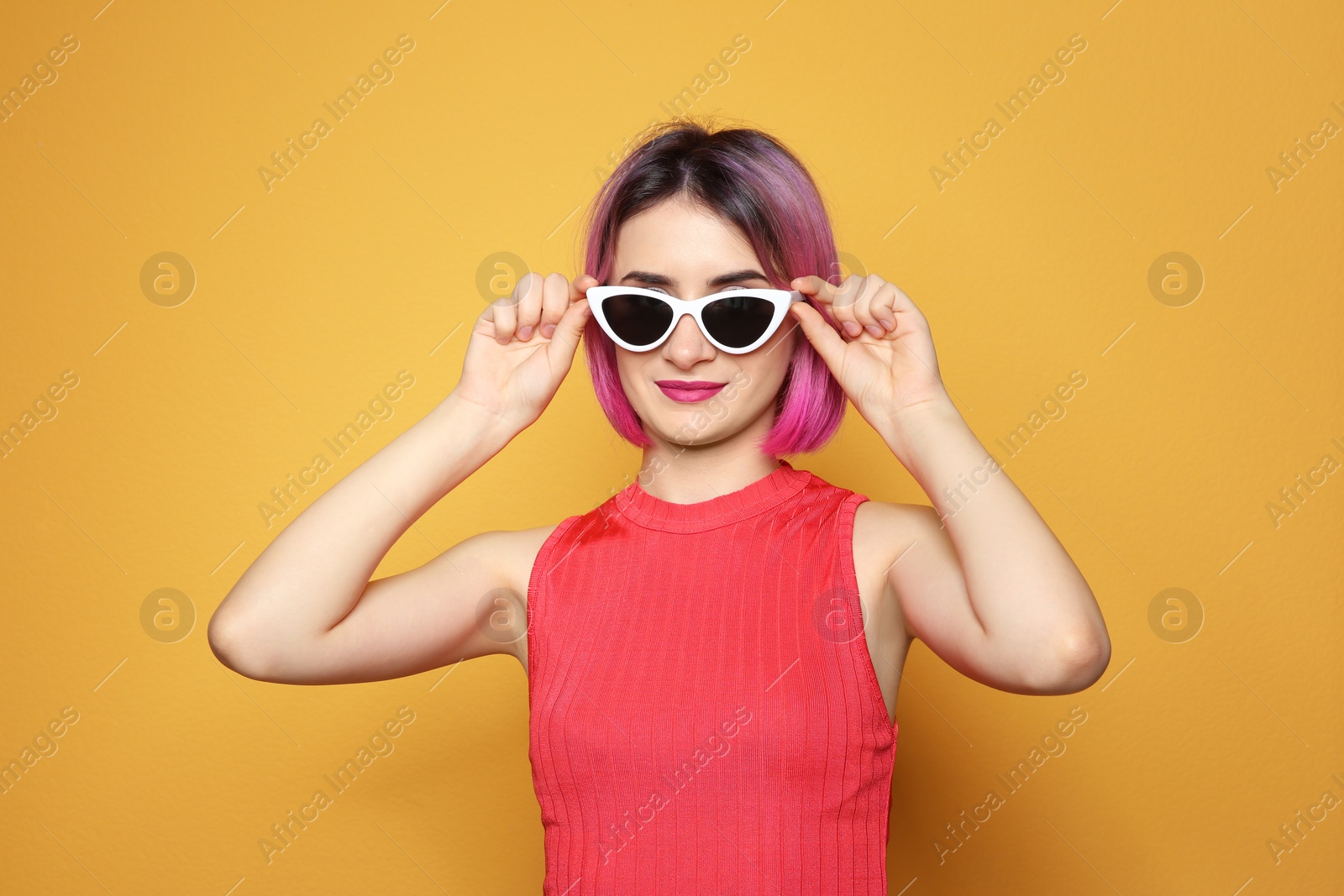 Photo of Young woman with trendy hairstyle wearing sunglasses against color background