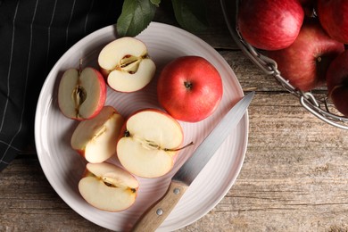Fresh red apples and knife on wooden table, flat lay