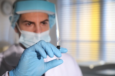 Doctor holding syringe with vaccine against Covid-19 in laboratory, focus on hand