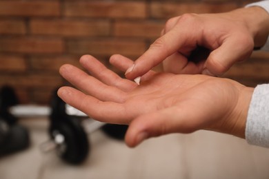 Man applying cream on hand for calluses treatment indoors, closeup